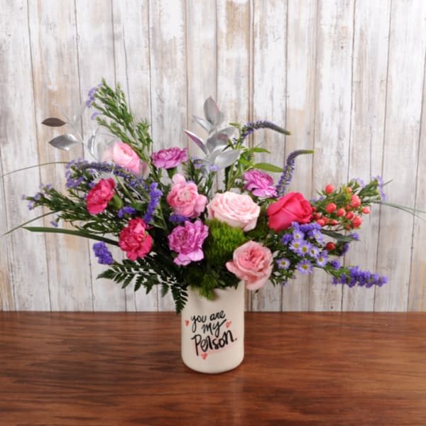 Pink roses and carnations with purple flowers in a white vase printed with 'you are my person'.