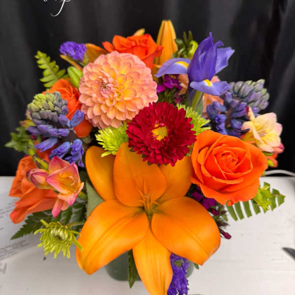 Bright mixed bouquet with orange lilies, roses, and purple blooms