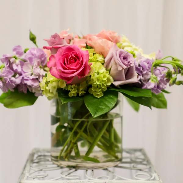 Pink and lavender roses with purple flowers in a glass vase