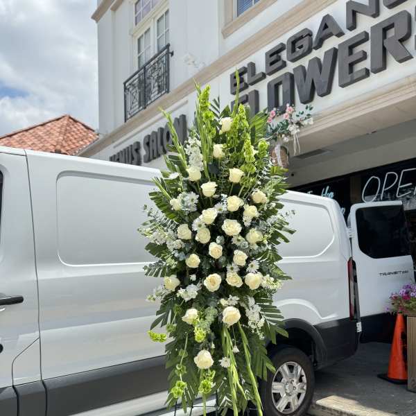 Tall standing floral spray with white roses and greenery on a metal easel
