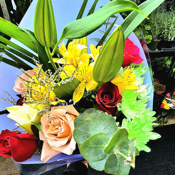 Bouquet of roses and yellow lilies wrapped in blue paper