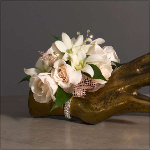 White roses and orchids arranged on a gold hand sculpture