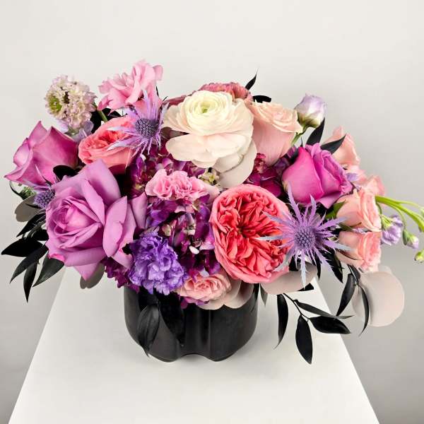 Pink, purple, and white floral arrangement in a black vase