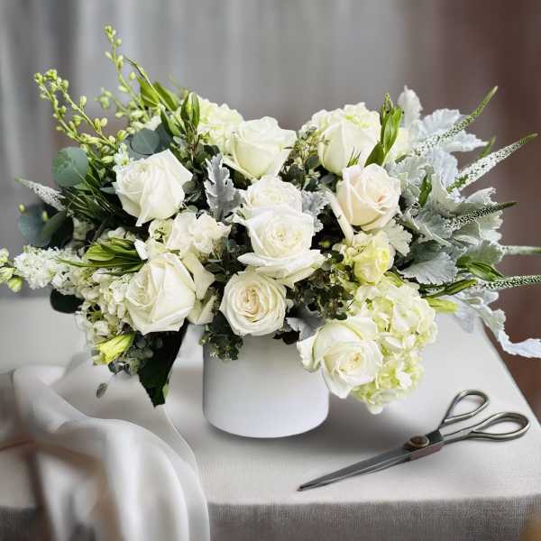 White rose bouquet in a white vase with silver foliage