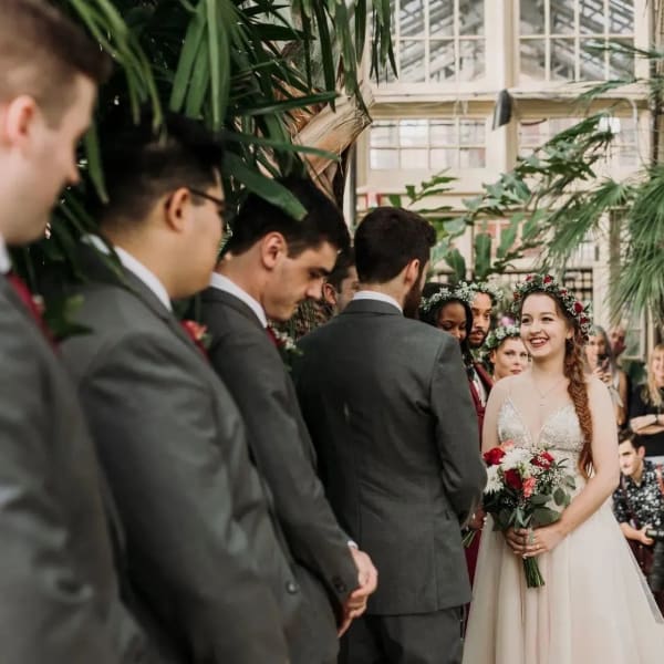Bride holding a red and white bouquet at an indoor wedding ceremony