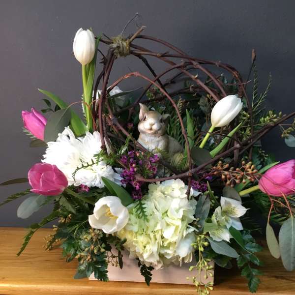 Floral arrangement with pink and white tulips, white blooms, and a rabbit figurine