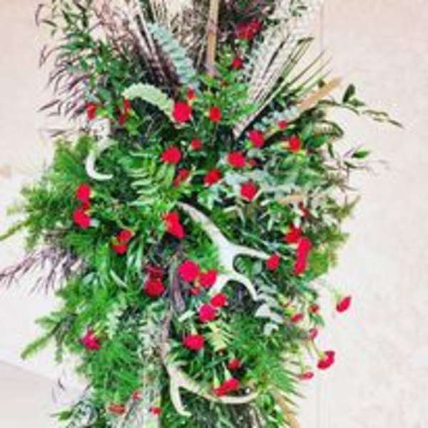 Tall floral arrangement with red blooms and mixed greenery