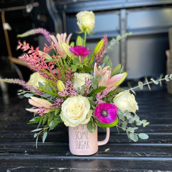 Pink mug vase with white roses, lilies, and a magenta anemone