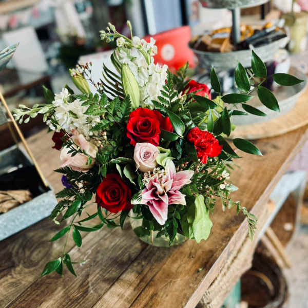 Mixed bouquet of red and pale pink roses with white blooms in a glass vase