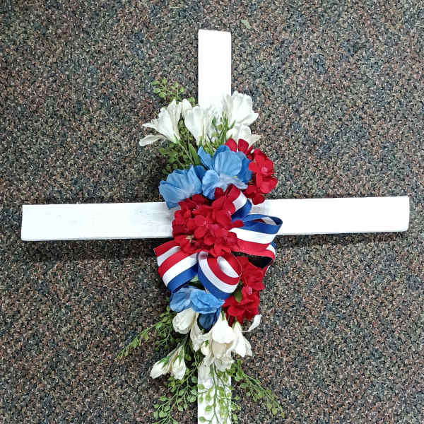 Floral cross with red, white, and blue flowers and ribbon