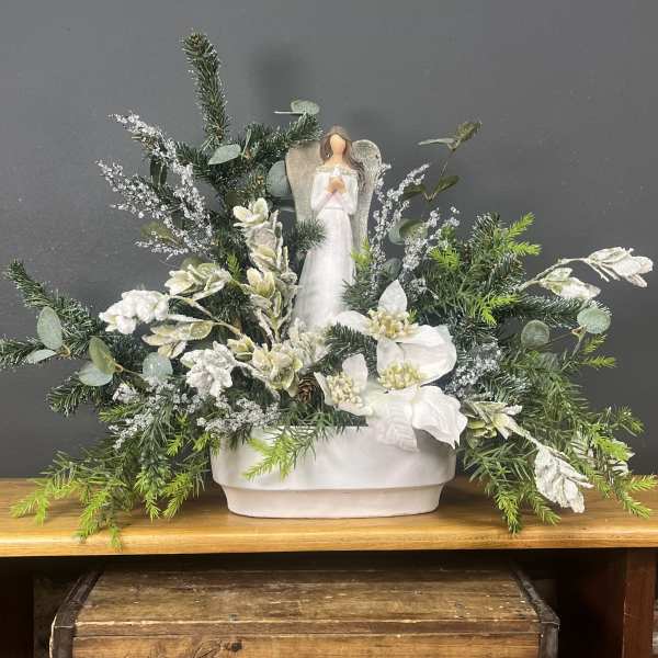 Winter floral arrangement with a small angel figurine in a white container