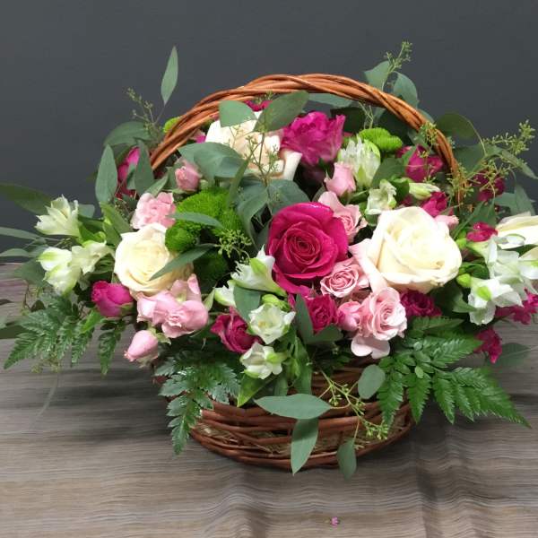 Basket of pink and white roses with greenery