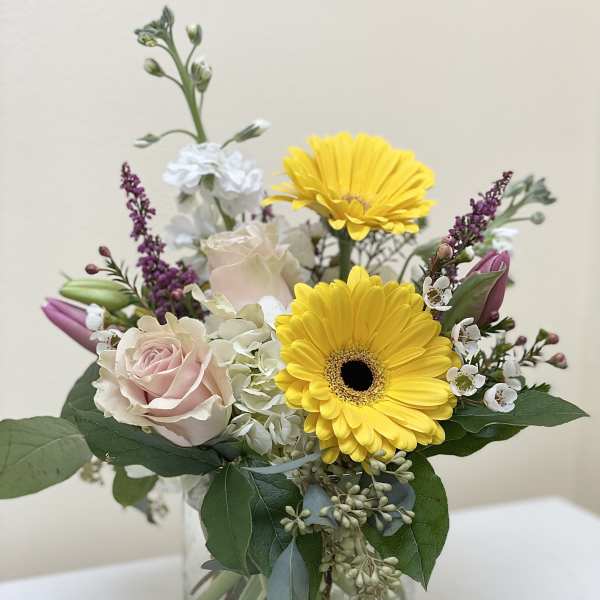 Bouquet of yellow gerbera daisies and pale pink roses in a glass vase
