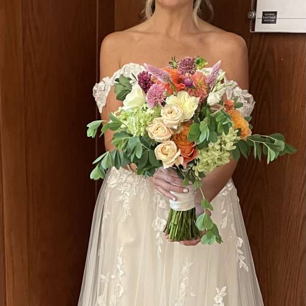 Bride holding a colorful bouquet of roses and mixed flowers