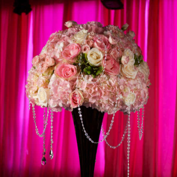 Pink and white rose arrangement in a tall black vase with hanging crystal strands