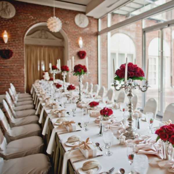 Long banquet table with red rose centerpieces and white candles