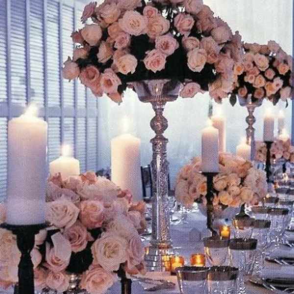 Pink rose centerpieces with white candles on a formal table setting
