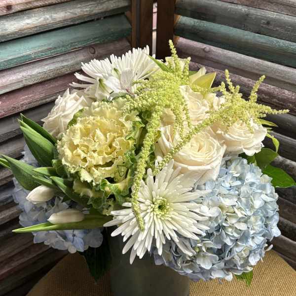 White roses, blue hydrangeas, and white daisies in a vase