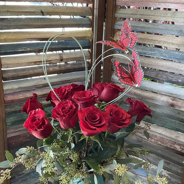 Red roses in a turquoise vase with butterfly picks