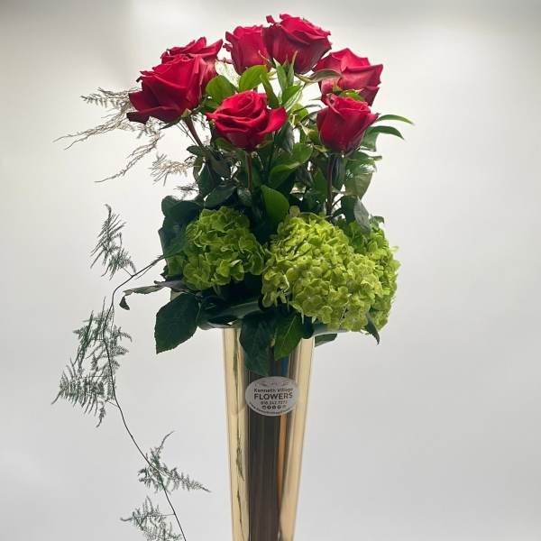 Tall vase arrangement with red roses and green hydrangeas