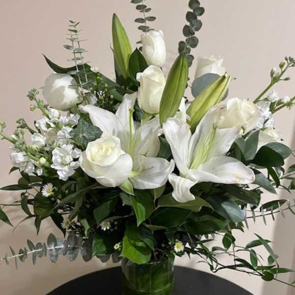 White lilies and roses arranged in a glass vase