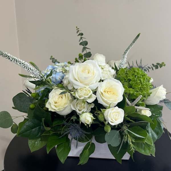 White roses and green hydrangea arranged in a low white container