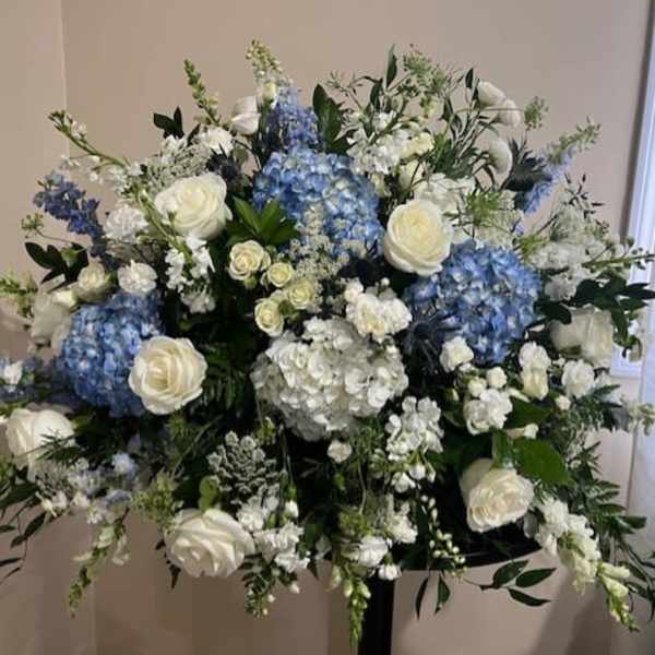 Large white and blue floral arrangement on a stand