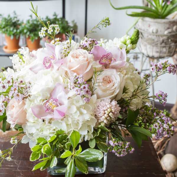 Pink roses and white hydrangeas in a glass vase with small accent flowers