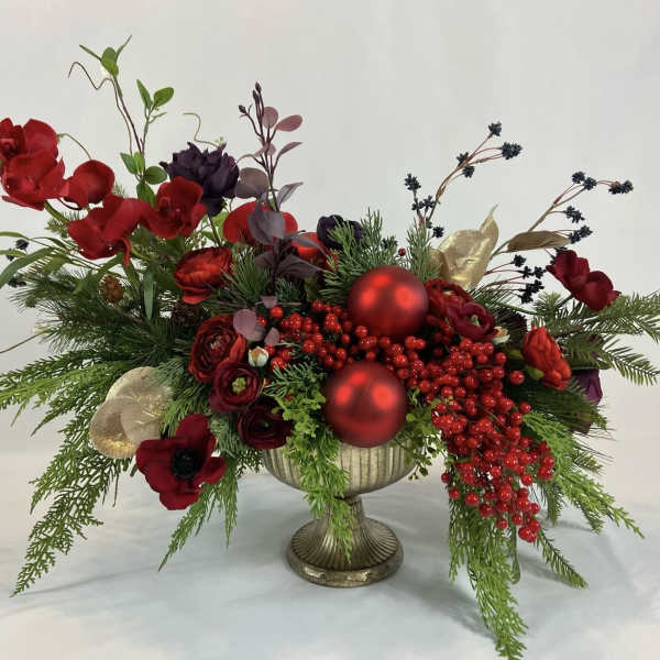 Red floral arrangement in a gold pedestal vase with berries and ornaments