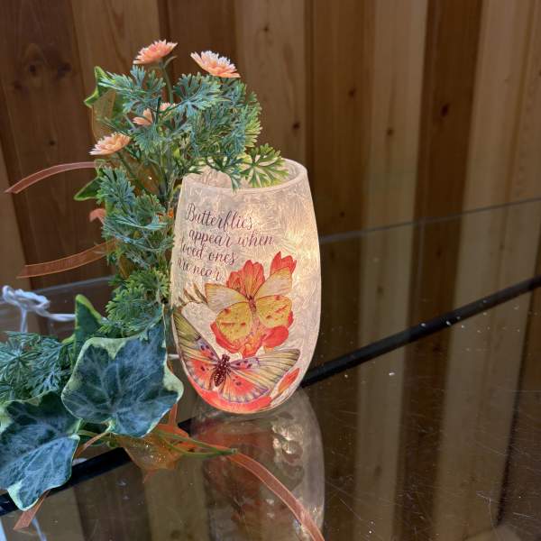 Butterfly-themed candle holder with faux flowers and ribbon