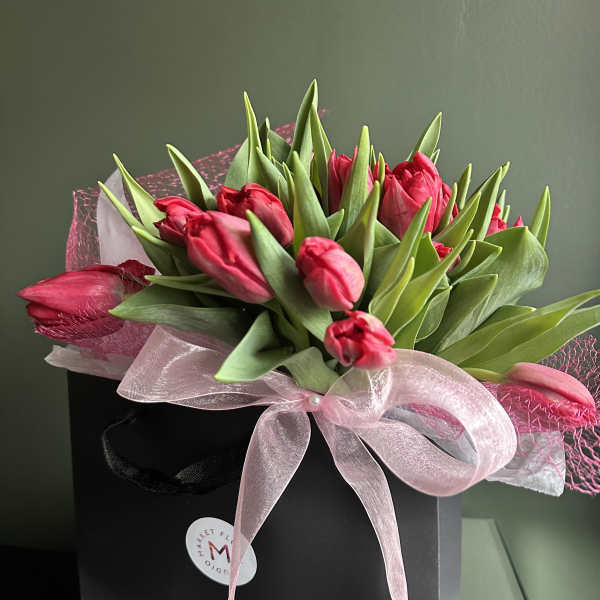 Pink tulips arranged in a black gift box with a pink ribbon