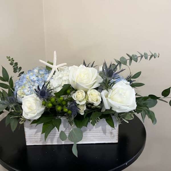 White and blue floral arrangement in a rectangular wooden box