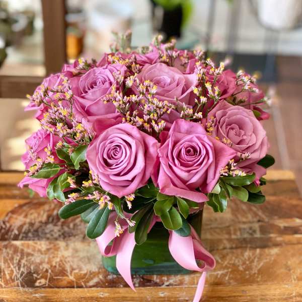 Pink rose bouquet in a glass vase with a pink ribbon