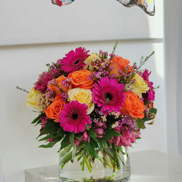 Bright mixed bouquet of roses and gerbera daisies in a clear glass vase