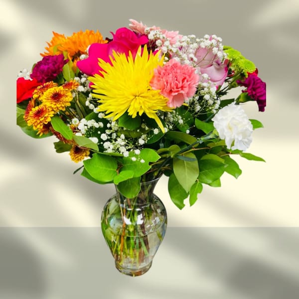 Mixed bouquet of bright flowers in a clear glass vase