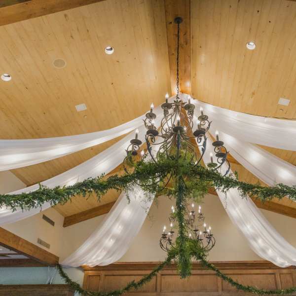 Chandelier draped with white fabric and greenery in a decorated hall