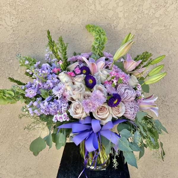 Lavender and blush mixed bouquet in a glass vase with a purple ribbon