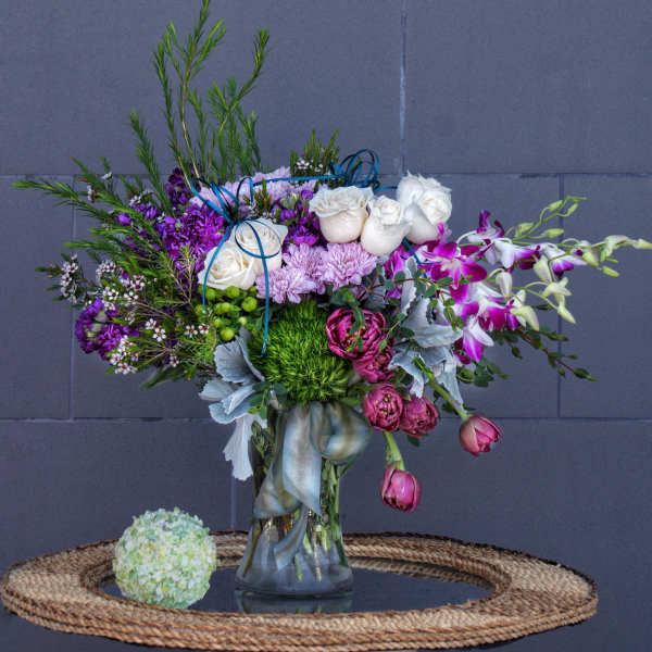 Mixed bouquet in a glass vase with white roses and purple orchids