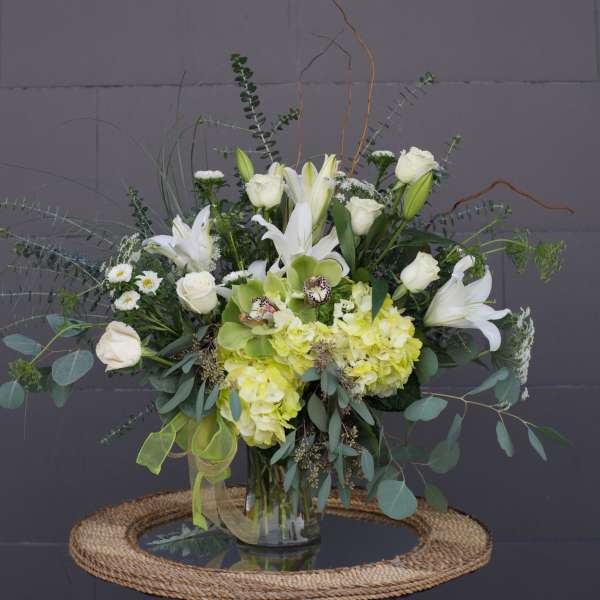 White lilies and roses with pale green hydrangeas in a glass vase