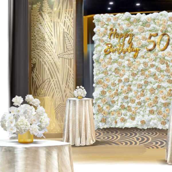 White floral wall with gold "Happy Birthday 50" lettering and matching table arrangements