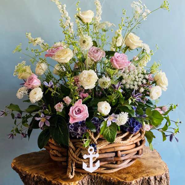 Basket arrangement of pink and white roses with delicate filler flowers