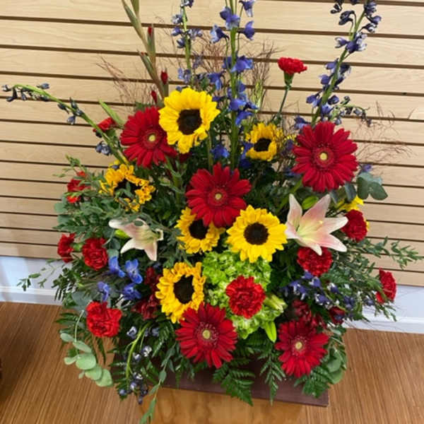 Tall mixed flower arrangement with sunflowers, red gerberas, and lilies
