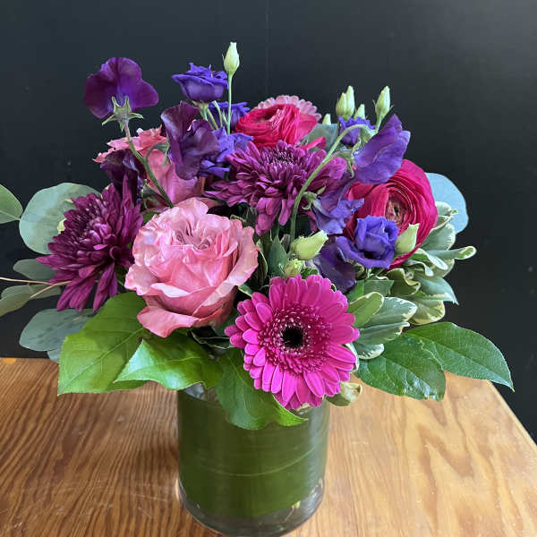 Mixed bouquet of pink, purple, and magenta flowers in a glass vase