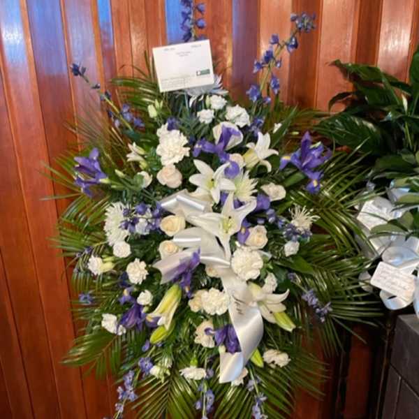 Standing floral spray with white and purple flowers and a white ribbon