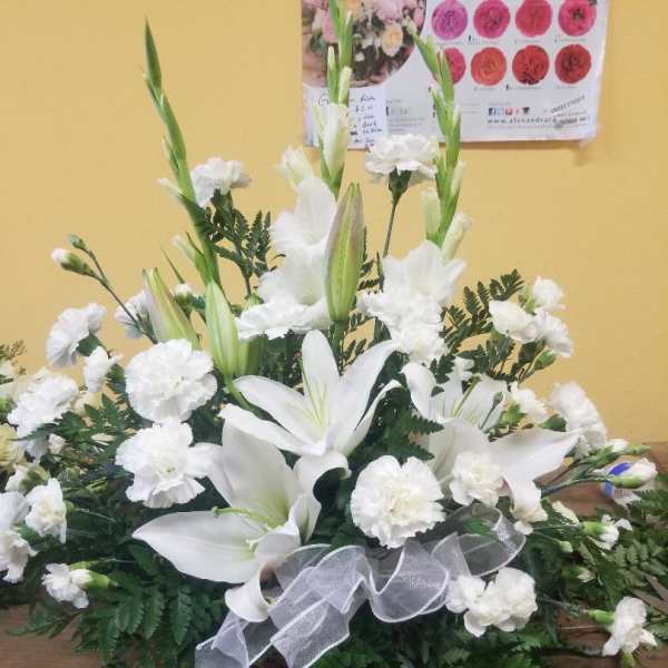 White lilies and carnations in a low arrangement with a silver ribbon