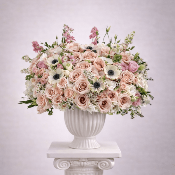 Blush and white rose arrangement in a white urn vase
