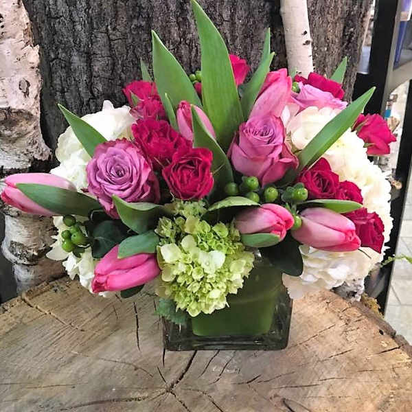 Pink and white floral arrangement in a square glass vase