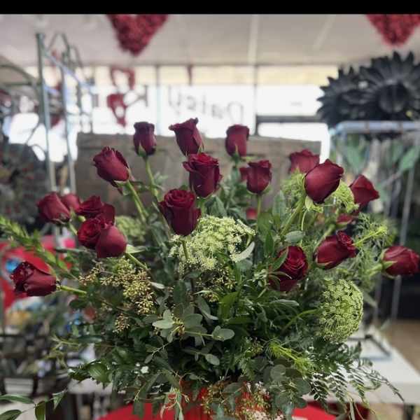 Red roses arranged in a red vase with greenery