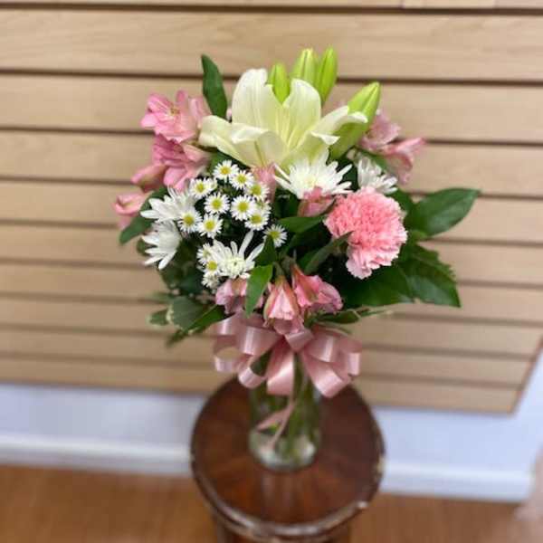 Pink and white mixed bouquet in a glass vase with a pink ribbon