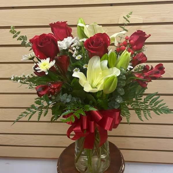 Red roses and white lilies in a glass vase with a red ribbon